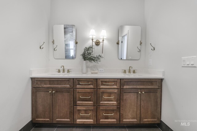 full bathroom with tile patterned flooring, baseboards, a sink, and double vanity