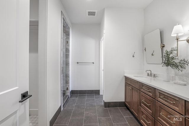 bathroom featuring vanity, baseboards, an enclosed shower, tile patterned flooring, and visible vents