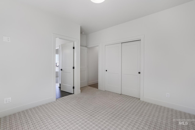 unfurnished bedroom with baseboards, carpet flooring, and a closet