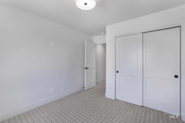 unfurnished bedroom with a closet, baseboards, and light carpet