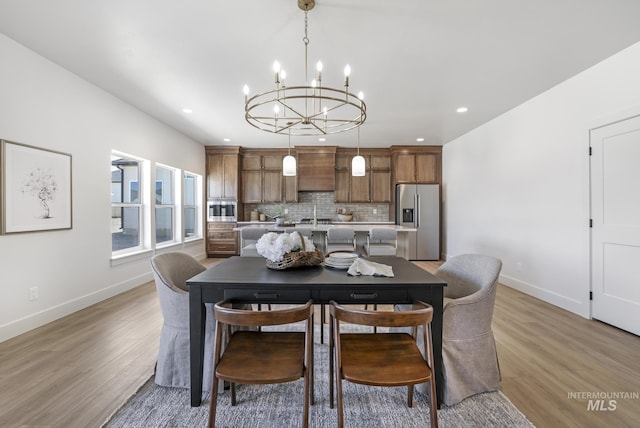 dining room featuring baseboards, a notable chandelier, light wood finished floors, and recessed lighting