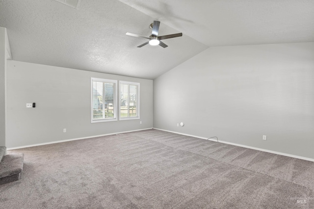 carpeted empty room featuring baseboards, vaulted ceiling, and ceiling fan