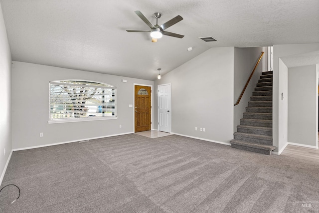 unfurnished living room featuring carpet floors, a ceiling fan, vaulted ceiling, and stairway