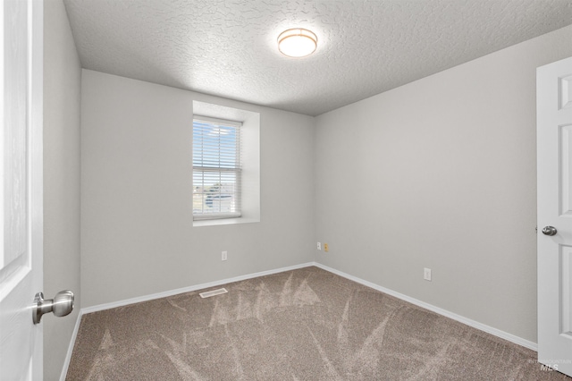 carpeted empty room featuring a textured ceiling, baseboards, and visible vents