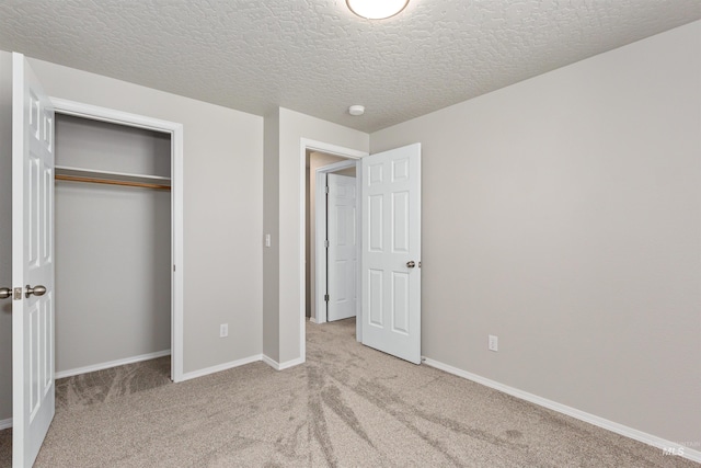 unfurnished bedroom featuring a textured ceiling, a closet, carpet flooring, and baseboards