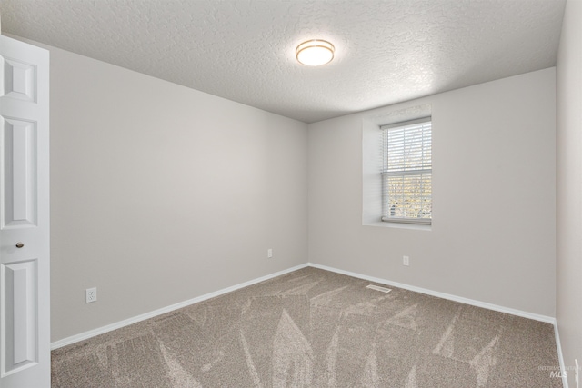 carpeted spare room featuring visible vents, baseboards, and a textured ceiling