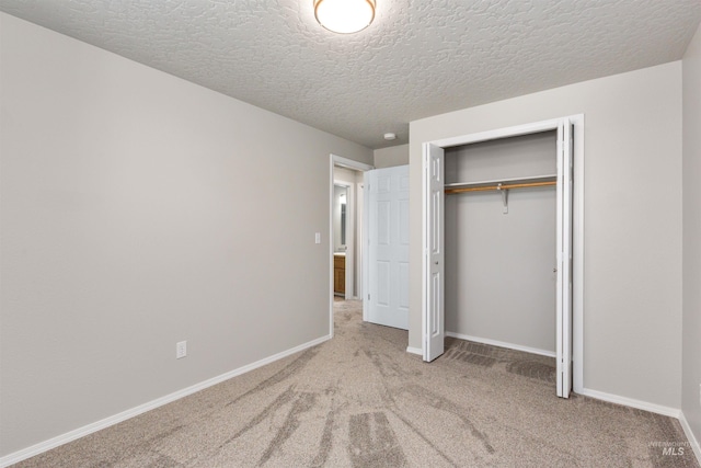 unfurnished bedroom with a textured ceiling, a closet, baseboards, and carpet floors