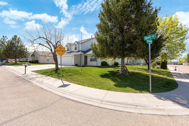 view of front of home featuring an attached garage, driveway, a front yard, and a residential view