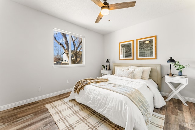 bedroom with ceiling fan, baseboards, and wood finished floors