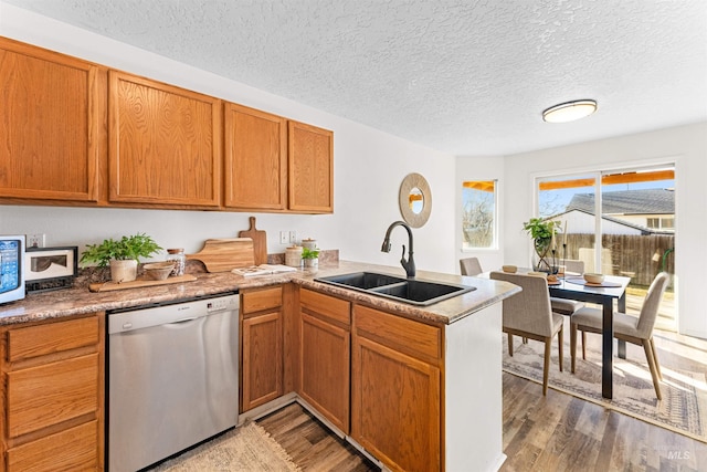 kitchen with a sink, light wood-type flooring, a peninsula, and stainless steel dishwasher