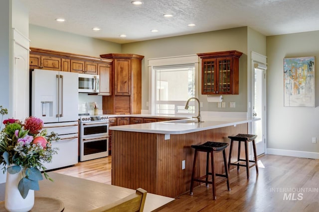 16089 N Basin Way, Boise, ID 83714 - kitchen featuring white refrigerator with ice dispenser, stainless steel microwave, double oven range, a peninsula, and light wood-style floors