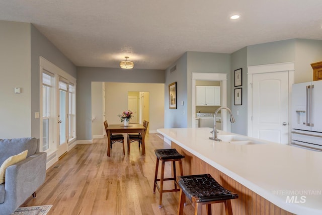 16089 N Basin Way, Boise, ID 83714 - kitchen featuring a sink, a kitchen bar, light wood-style floors, baseboards, and light countertops