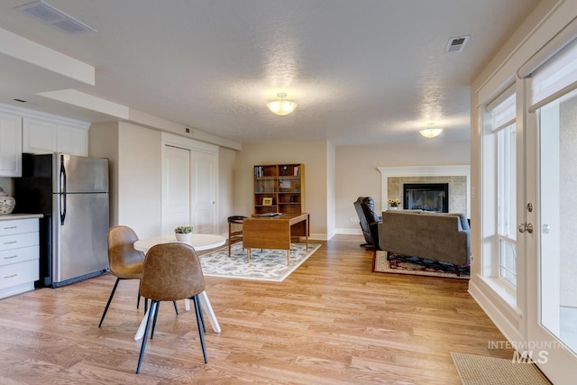 16089 N Basin Way, Boise, ID 83714 - dining space with light wood finished floors, healthy amount of natural light, a fireplace, and a textured ceiling