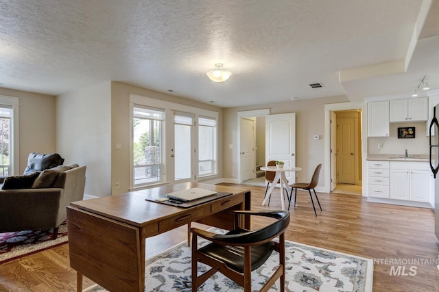 16089 N Basin Way, Boise, ID 83714 - dining space featuring a textured ceiling, light wood finished floors, a desk, and baseboards