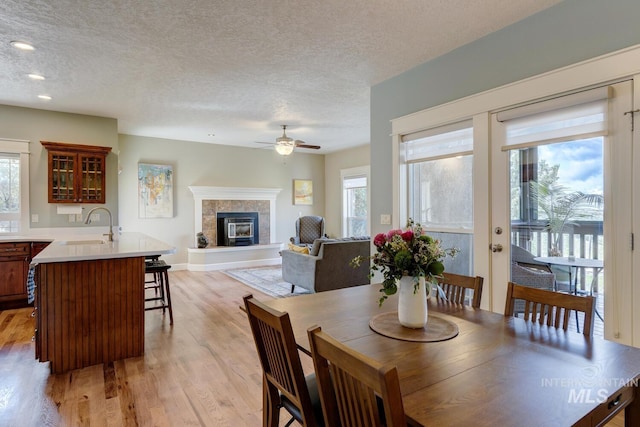 16089 N Basin Way, Boise, ID 83714 - dining room with ceiling fan, a tiled fireplace, healthy amount of natural light, light wood-style floors, and a textured ceiling