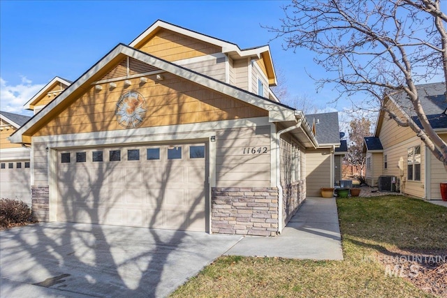 view of front of home featuring cooling unit, stone siding, an attached garage, and driveway