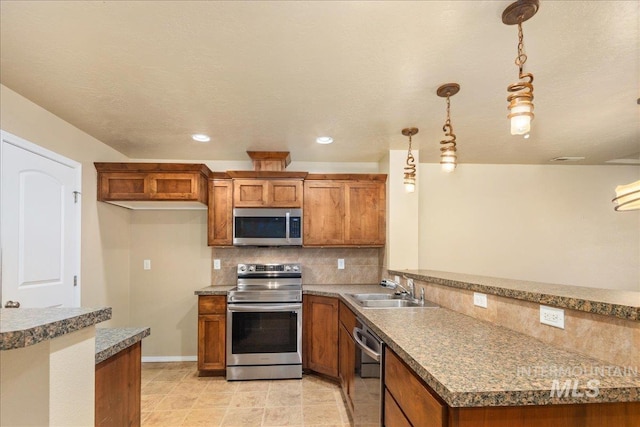 kitchen with brown cabinetry, a peninsula, stainless steel appliances, and a sink