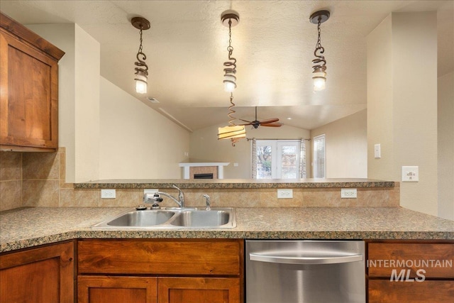 kitchen with brown cabinetry, a sink, lofted ceiling, and stainless steel dishwasher