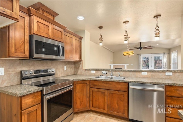 kitchen with tasteful backsplash, brown cabinets, appliances with stainless steel finishes, and a sink