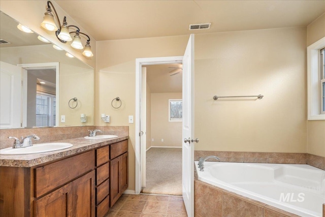 bathroom with a bath, visible vents, double vanity, and a sink