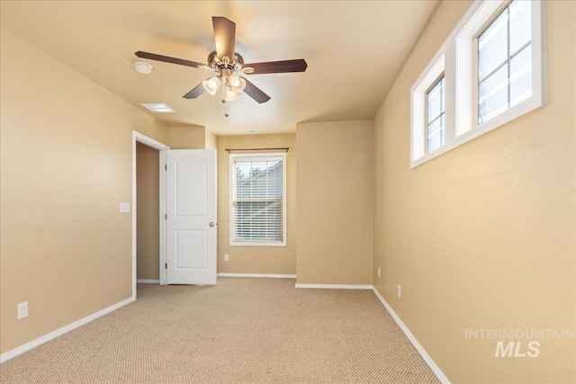 spare room featuring visible vents, light colored carpet, baseboards, and ceiling fan