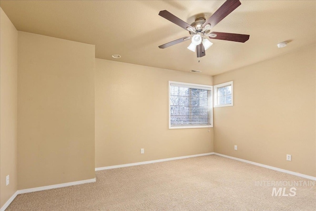 spare room with visible vents, baseboards, light colored carpet, and ceiling fan