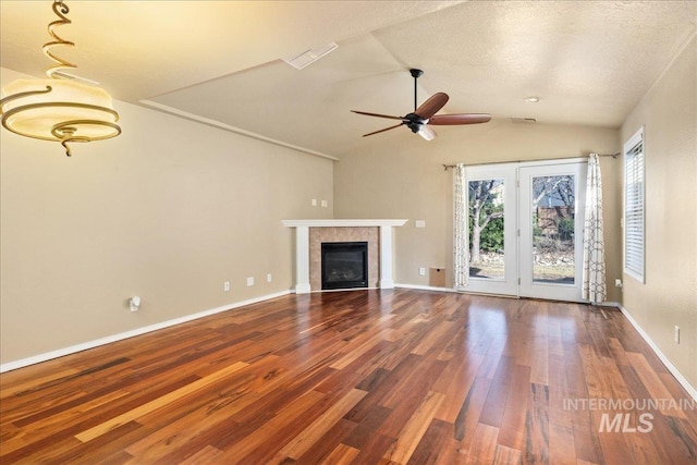 unfurnished living room with baseboards, lofted ceiling, wood finished floors, and a tile fireplace