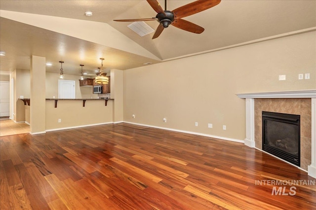 unfurnished living room featuring baseboards, wood finished floors, a fireplace, and vaulted ceiling