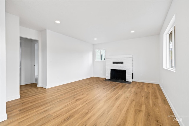 unfurnished living room featuring a brick fireplace and light wood-type flooring