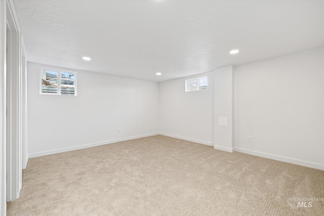 basement featuring a textured ceiling and light colored carpet