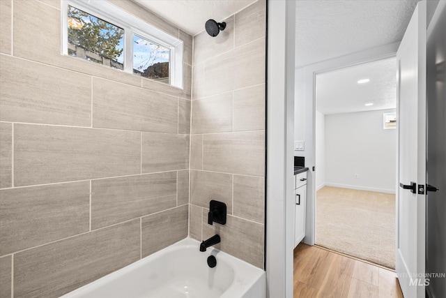 bathroom featuring vanity, tiled shower / bath combo, hardwood / wood-style flooring, and a textured ceiling