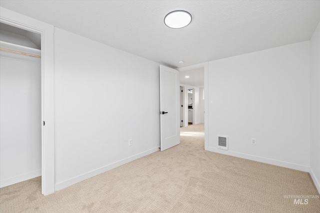 unfurnished bedroom with light carpet and a closet