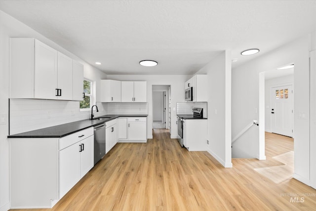 kitchen featuring white cabinets, stainless steel appliances, and light wood-type flooring