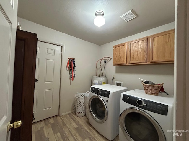 1585 Woodside Rd, Winchester, ID 83555 - laundry area featuring cabinet space, independent washer and dryer, light wood-type flooring, and water heater