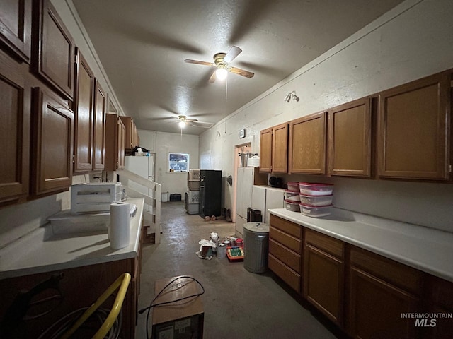 1585 Woodside Rd, Winchester, ID 83555 - kitchen with a ceiling fan, concrete flooring, light countertops, brown cabinetry, and freestanding refrigerator