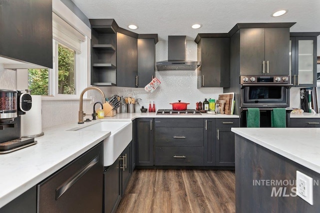 kitchen with light stone countertops, sink, wall chimney exhaust hood, dark wood-type flooring, and appliances with stainless steel finishes