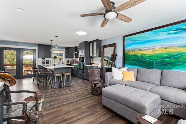 living room with french doors, a textured ceiling, ceiling fan, sink, and dark hardwood / wood-style floors