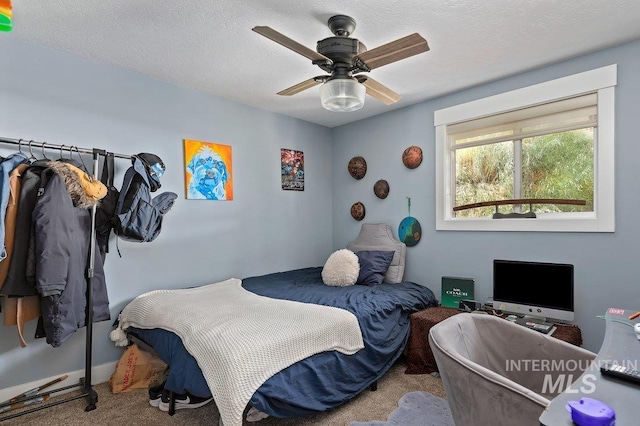 carpeted bedroom with ceiling fan and a textured ceiling