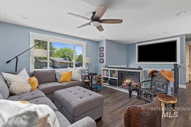 living room featuring a fireplace, ceiling fan, dark hardwood / wood-style flooring, and a textured ceiling