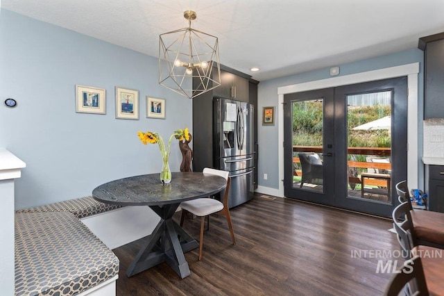 dining space featuring dark hardwood / wood-style flooring, french doors, and an inviting chandelier