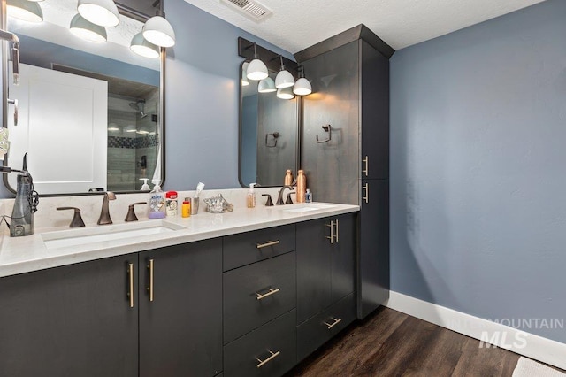 bathroom featuring vanity, wood-type flooring, a textured ceiling, and walk in shower