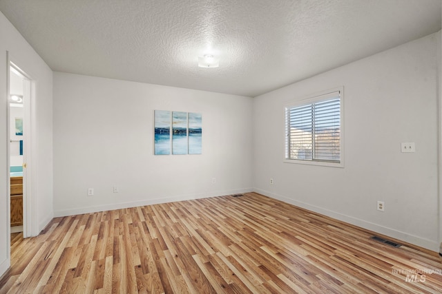 spare room with a textured ceiling and light wood-type flooring