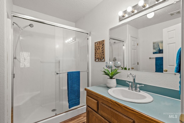 bathroom with vanity, wood-type flooring, a textured ceiling, and walk in shower