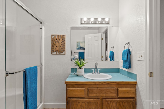 bathroom with a shower with door and vanity