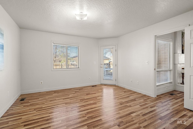 empty room featuring a textured ceiling and light hardwood / wood-style flooring