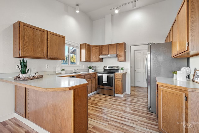 kitchen with kitchen peninsula, high vaulted ceiling, light hardwood / wood-style flooring, and stainless steel range with electric stovetop