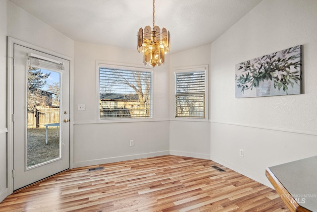 dining space with a chandelier, light wood-type flooring, and plenty of natural light