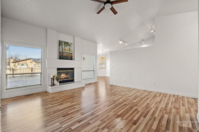 unfurnished living room with light wood-type flooring, vaulted ceiling, and ceiling fan