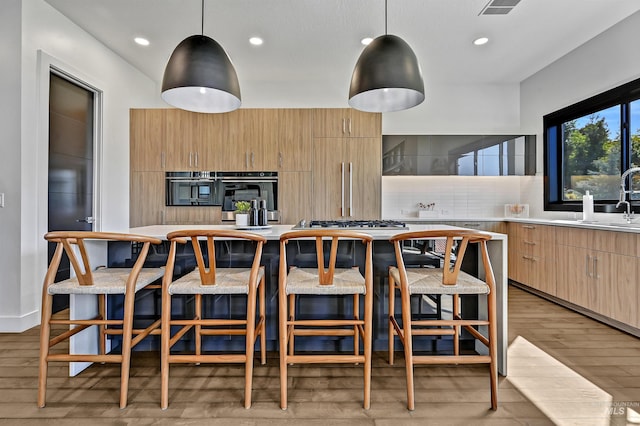 kitchen featuring light wood finished floors, decorative light fixtures, light countertops, decorative backsplash, and recessed lighting