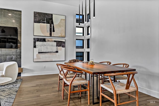 dining space with a high ceiling, baseboards, and hardwood / wood-style flooring